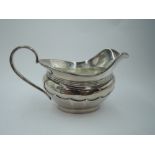 A silver cream jug having facetted decoration, rub over rim and loop handle, London 1945, makers
