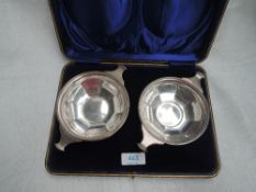 A cased pair of early 20th Century silver quaichs of circular form having facetted decoration to