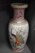 A large standing Cantonese styled floor vase having peacock enamel scene and standing at 60cm tall