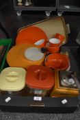 A collection of retro tupperware including orange Melaware plates and cups.