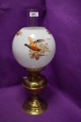 A vintage brass bodied oil burning lamp with game bird and pheasant design shade