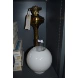 A brass oil lamp with chimney and shade.