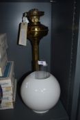 A brass oil lamp with chimney and shade.