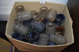 A box full of vintage glass lanterns or candle holders, various colours.