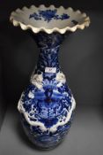 A large standing blue and white wear Chinese vase having raised dragon motif and scalloped rim