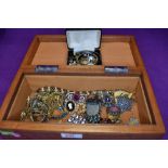 A treen jewellery box containing a small selection of costyume jewellery including brooches, wrist