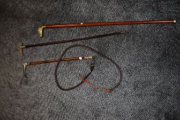 A riding crop and three canes,one with brass horse head another with a horn handle.