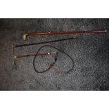 A riding crop and three canes,one with brass horse head another with a horn handle.