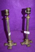 A pair of antique brass cast candle sticks having column stems of crucifix bases