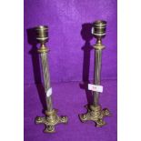 A pair of antique brass cast candle sticks having column stems of crucifix bases