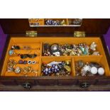 A small wooden jewellery box containing a selection of stud and clip earrings