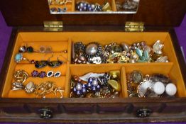 A small wooden jewellery box containing a selection of stud and clip earrings