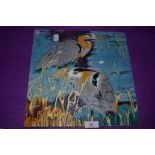 A large ceramic tile of two heron birds signed Pierce