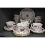 A collection of vintage cups, saucers,cake plate and more, having pink rose pattern and gilt