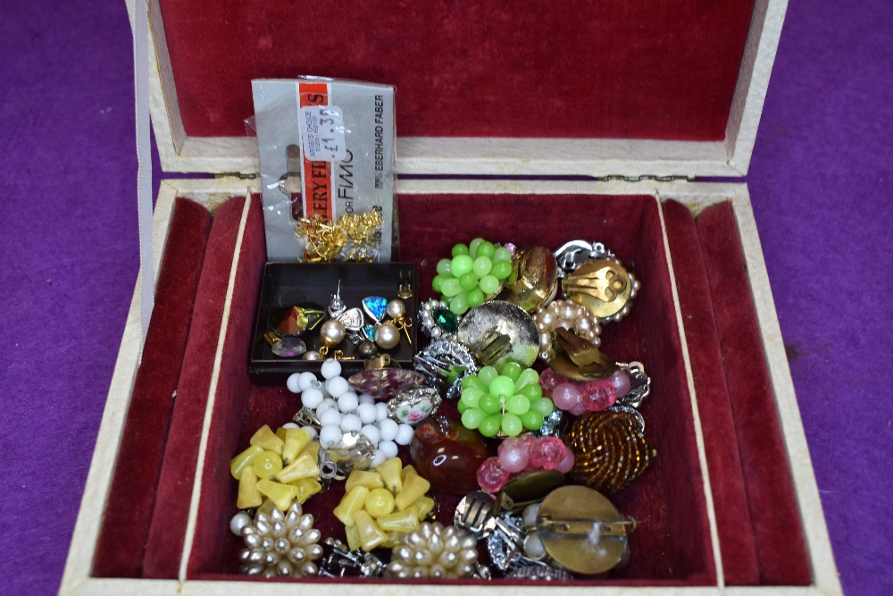 A small vintage jewellery box containing a selection of earrings including clip and stud