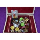 A small vintage jewellery box containing a selection of earrings including clip and stud