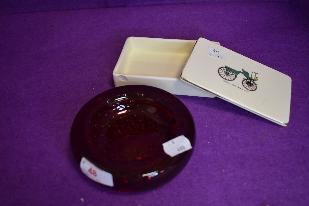 A ruby red control bubble glass dish and ceramic lidded container with transport imagery