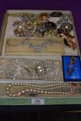 A vintage chocolate box containing a selection of costume brooches and necklaces including crystal