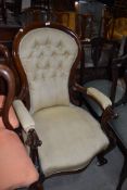 A traditional nursing chair having carved mahogany frame work with button back upholstery