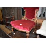 An antique nursing chair having carved banded and turned frame with red velvet upholstery