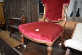 An antique nursing chair having carved banded and turned frame with red velvet upholstery