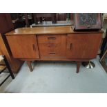 A vintage sideboard, compact size with central three drawer section flanked by cupboards, tapered