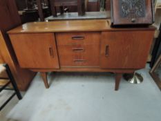 A vintage sideboard, compact size with central three drawer section flanked by cupboards, tapered