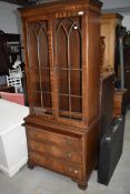 A reproduction Regency style bookcase/drinks cabinet having drawer base, lion mask handles and slide