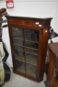 An Edwardian corner cupboard having rolled glass front