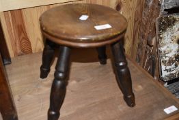 A traditional oak topped four legged milking stool