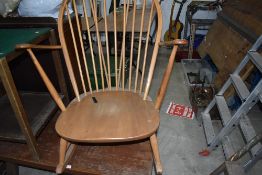 A mid century light stained rocking arm chair by Ercol having blue badge