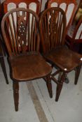 A pair of traditional oak wheel back solid seat kitchen chairs