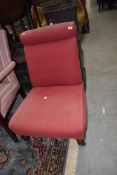 A low nursing or bedroom chair having oak frame with red upholstery