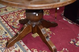 A modern oak circular dining table having bulbous column and chunky legs