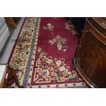 A traditional room sized carpet square, having red ground and floral vase pattern