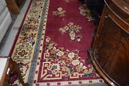 A traditional room sized carpet square, having red ground and floral vase pattern