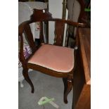 A traditional corner chair having mahogany frame with arms and carved back