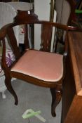 A traditional corner chair having mahogany frame with arms and carved back