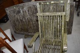 A teak garden table and pair of folding chairs, in need of some restoration