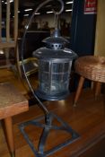 A lantern style candle stand on wrought iron frame