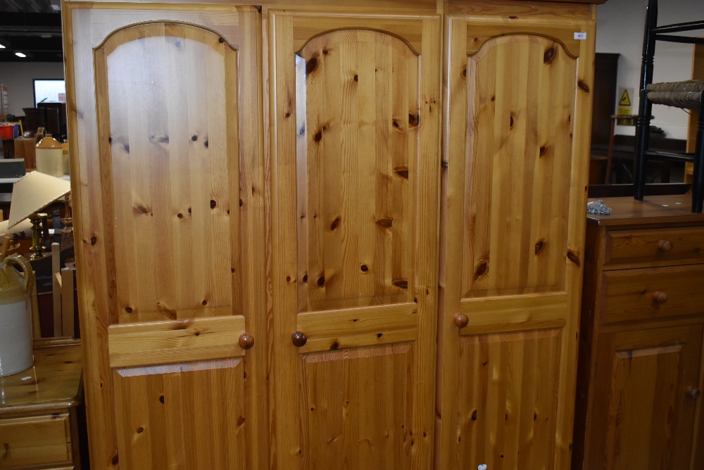 A modern pine triple wardrobe having drawer base