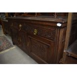 A 19th Century oak sideboard having panelled ledge back, carved drawer and door fronts with brass