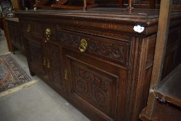 A 19th Century oak sideboard having panelled ledge back, carved drawer and door fronts with brass