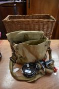 A wicker basket containing canvas bag with tackle and two reels.