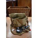 A wicker basket containing canvas bag with tackle and two reels.