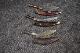 Three large Kukhri's all in leather scabbards, one having two small knives, one having one small