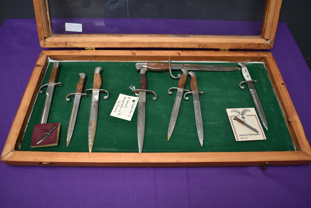 A wood and glass small display case containing a collection of 8 Miniature Bayonets with Quillions