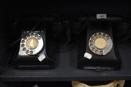 A pair of traditional bakelite telephones one having name badge for Call Exchange