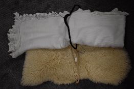 A large white crotchet work table cloth and a sheep skin rug