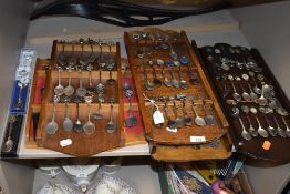 Five display shelves containing various collectable spoons including some HM silver